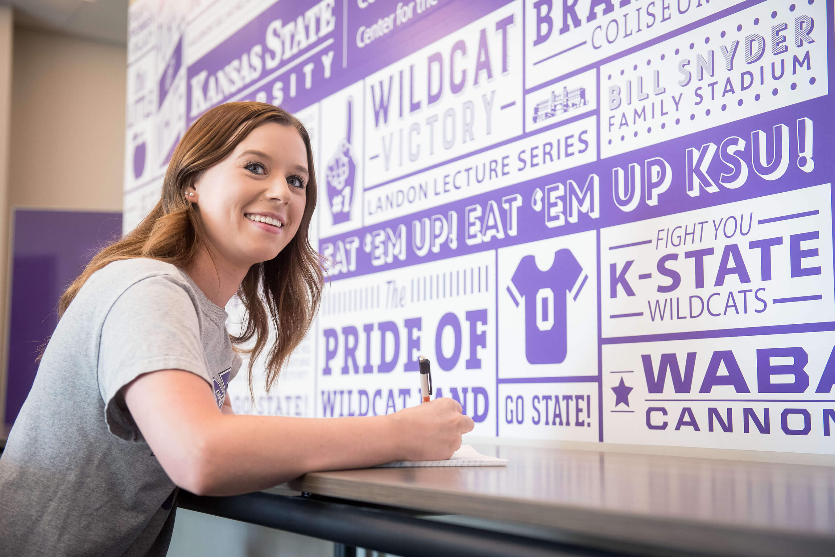 happy student in front of k-state sign